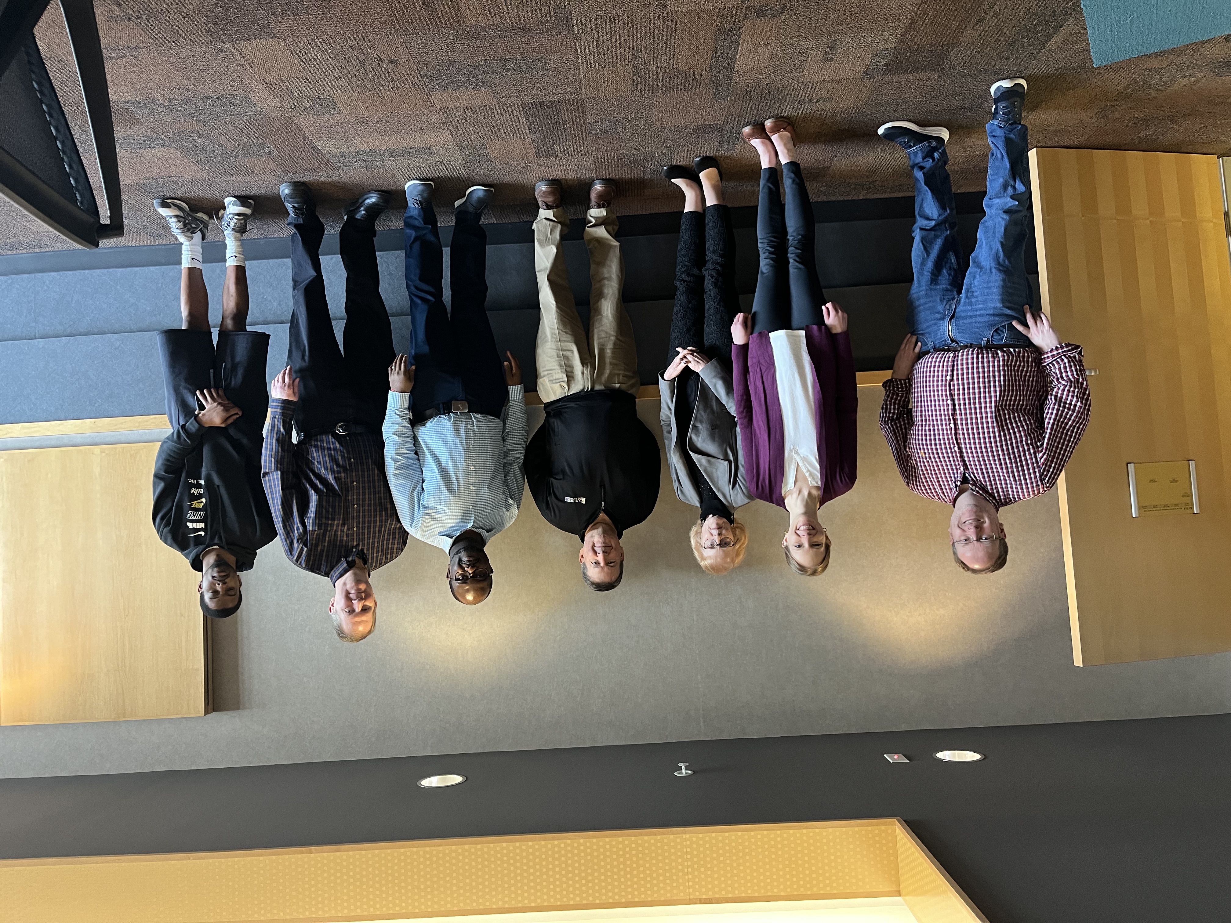 Six people standing in front of a wall